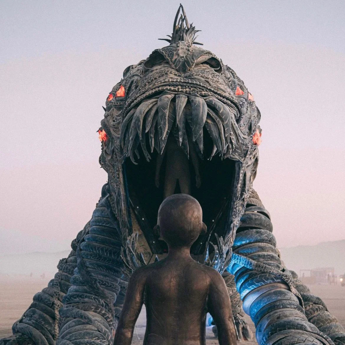 Child sculpture facing the Fearbeast at dawn with red LED eyes glowing